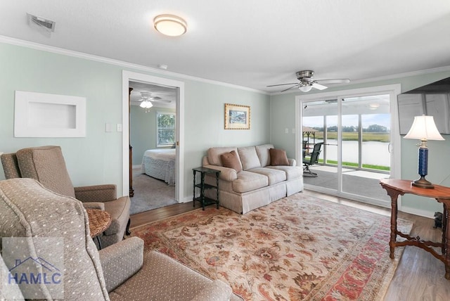 living room featuring hardwood / wood-style floors, ceiling fan, a water view, and ornamental molding