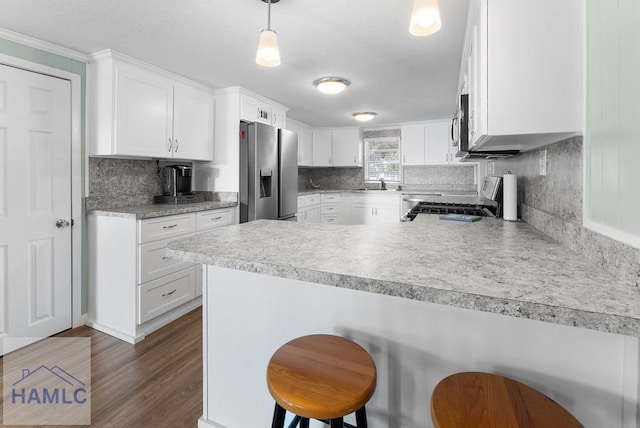 kitchen featuring a kitchen bar, kitchen peninsula, stainless steel appliances, white cabinets, and hanging light fixtures