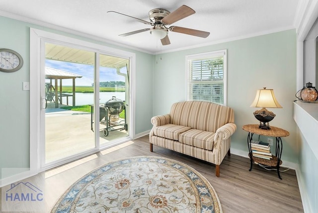 sitting room with ceiling fan, a wealth of natural light, a water view, and hardwood / wood-style flooring