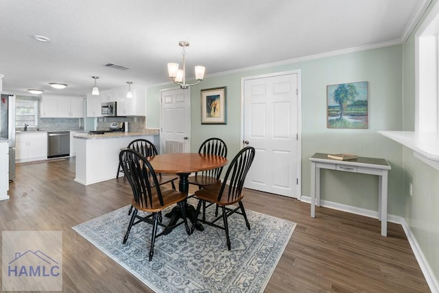 dining space with dark hardwood / wood-style floors, crown molding, a notable chandelier, and sink