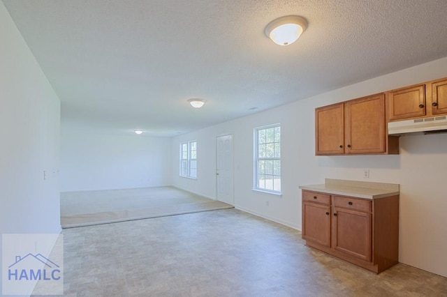 1 Blackberry Ln, Port Wentworth, GA 31407 - kitchen featuring under cabinet range hood, brown cabinets, light countertops, open floor plan, and a textured ceiling