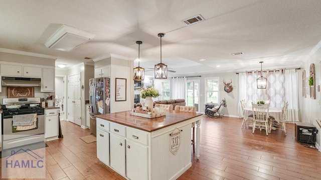 705 S 11th St, Jesup, GA 31545 - kitchen featuring appliances with stainless steel finishes, under cabinet range hood, light wood-style flooring, wooden counters, and white cabinets