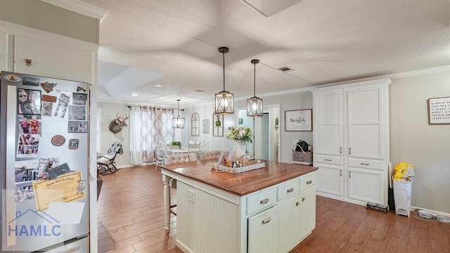705 S 11th St, Jesup, GA 31545 - kitchen with freestanding refrigerator, wooden counters, wood-type flooring, white cabinets, and a breakfast bar area