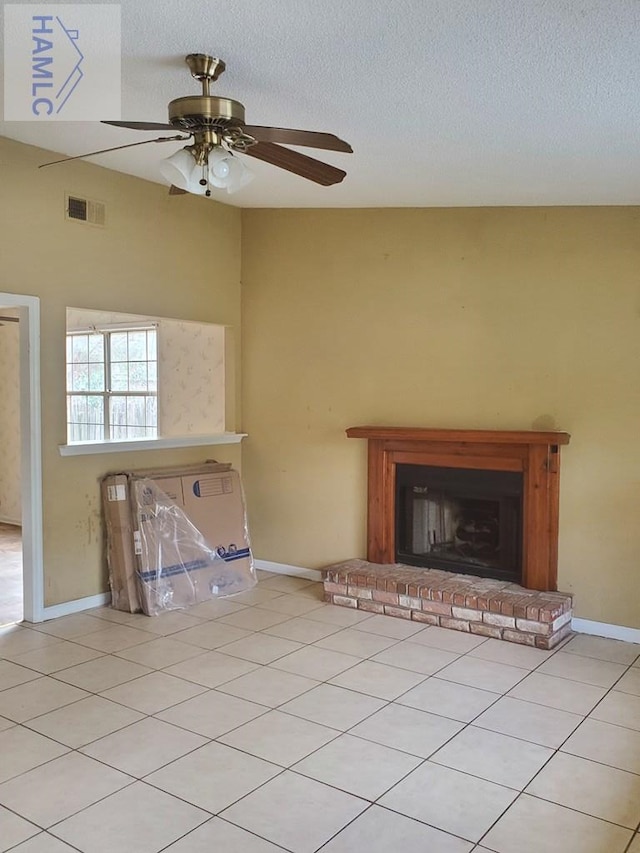 unfurnished living room with ceiling fan, a textured ceiling, and a brick fireplace