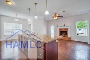 kitchen with light stone countertops, dark hardwood / wood-style flooring, decorative light fixtures, and ceiling fan