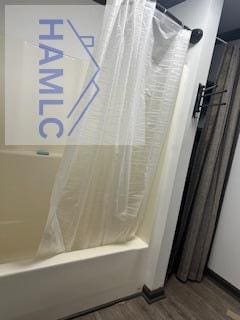 bathroom featuring shower / bathtub combination with curtain and hardwood / wood-style floors