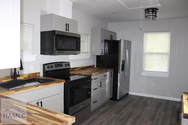 kitchen with dark wood-type flooring, stainless steel appliances, butcher block counters, and sink