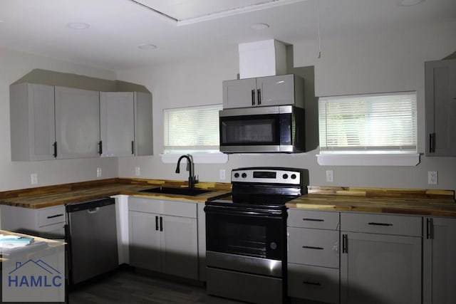 kitchen featuring butcher block countertops, sink, dark hardwood / wood-style floors, and appliances with stainless steel finishes