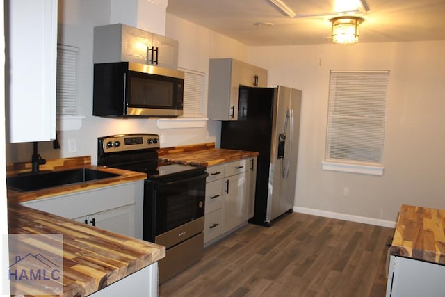 kitchen featuring dark hardwood / wood-style flooring, white cabinets, stainless steel appliances, and wood counters