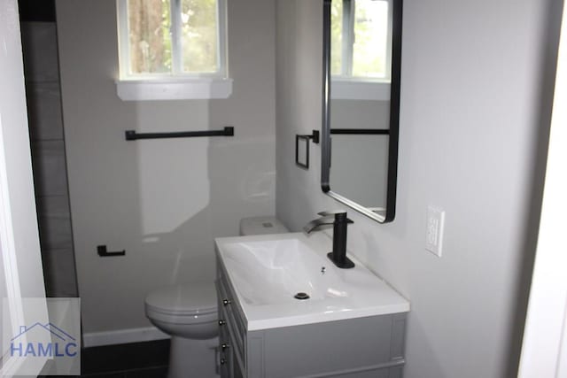 bathroom with tile patterned flooring, vanity, a healthy amount of sunlight, and toilet