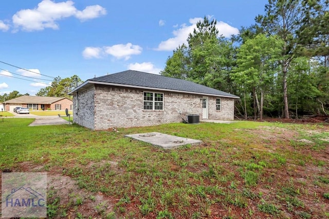 back of house featuring brick siding, a lawn, and central air condition unit