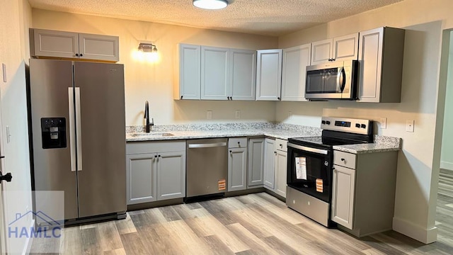 30 Cypress Cv NE, Ludowici, GA 31316 - kitchen with appliances with stainless steel finishes, gray cabinetry, light wood finished floors, light stone countertops, and a textured ceiling