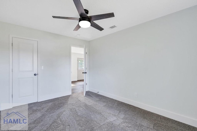 carpeted empty room with ceiling fan, visible vents, and baseboards