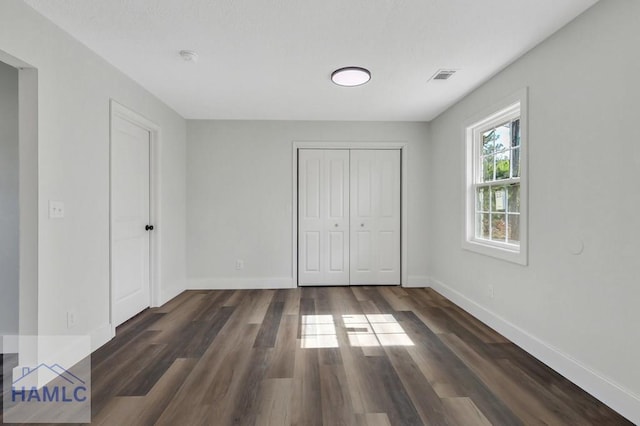 unfurnished bedroom featuring visible vents, baseboards, wood finished floors, and a closet