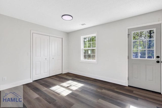 interior space featuring visible vents, dark wood finished floors, and baseboards
