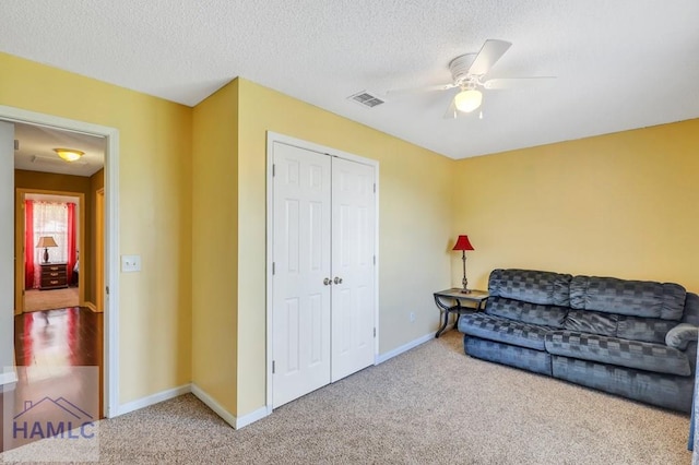 sitting room featuring ceiling fan, carpet, and a textured ceiling