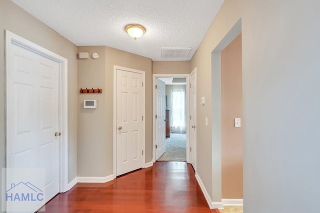 hallway with a textured ceiling and dark wood-type flooring