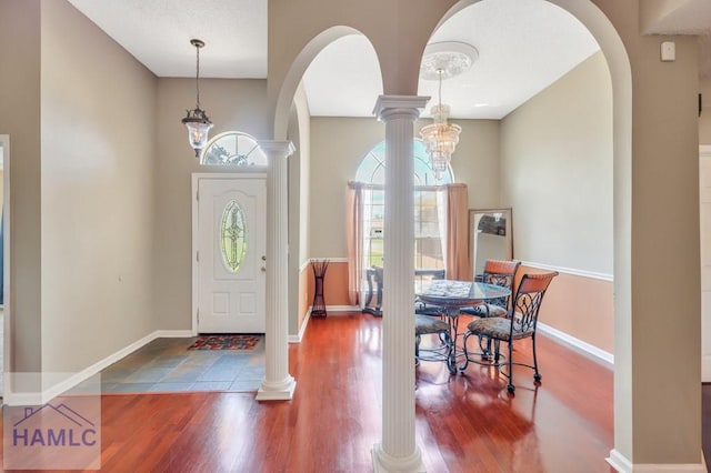 entryway with ornate columns, dark hardwood / wood-style flooring, and a notable chandelier