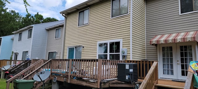 rear view of property featuring a wooden deck, central AC unit, and french doors