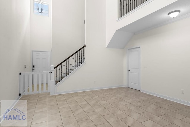 staircase featuring crown molding, a towering ceiling, and an inviting chandelier