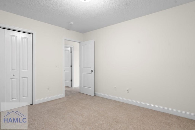 unfurnished bedroom with light carpet, a textured ceiling, and a closet