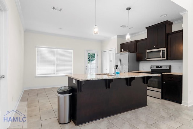 kitchen with a kitchen bar, appliances with stainless steel finishes, pendant lighting, and an island with sink