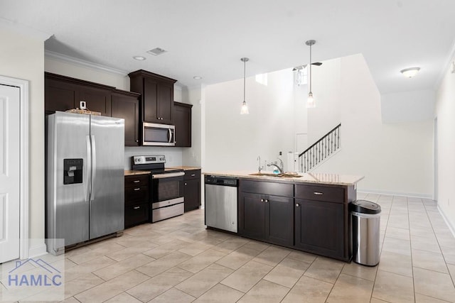 kitchen featuring appliances with stainless steel finishes, dark brown cabinets, sink, decorative light fixtures, and an island with sink