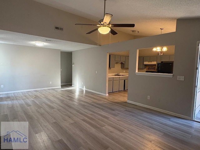 unfurnished living room featuring visible vents, a textured ceiling, wood finished floors, and a sink