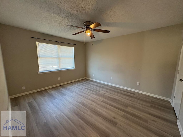 unfurnished room with a textured ceiling, baseboards, and wood finished floors