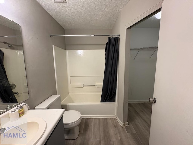 full bathroom with shower / bath combo with shower curtain, toilet, a textured ceiling, wood finished floors, and vanity