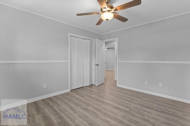 unfurnished bedroom featuring wood finished floors, baseboards, ornamental molding, a closet, and a ceiling fan
