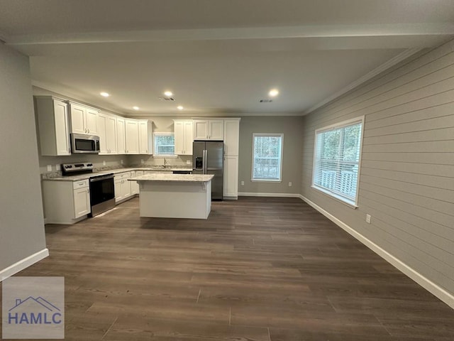 kitchen featuring dark wood-type flooring, stainless steel appliances, a center island, ornamental molding, and white cabinetry