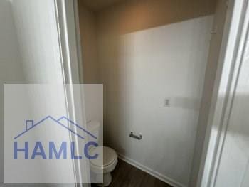 bathroom featuring wood finished floors, toilet, and baseboards