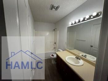 full bath featuring shower / tub combination, vanity, toilet, wood finished floors, and a textured ceiling
