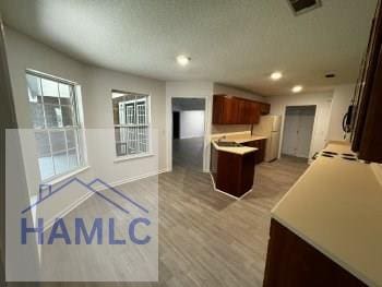 kitchen featuring light wood-style floors, light countertops, recessed lighting, freestanding refrigerator, and open floor plan