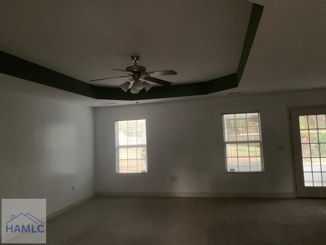 carpeted empty room featuring a tray ceiling and ceiling fan