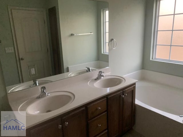 bathroom featuring a tub, plenty of natural light, and vanity