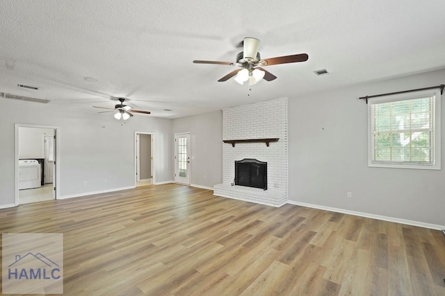 265 Mahan St, Jesup, GA 31545 - unfurnished living room with washer / clothes dryer, ceiling fan, light wood finished floors, a textured ceiling, and a brick fireplace