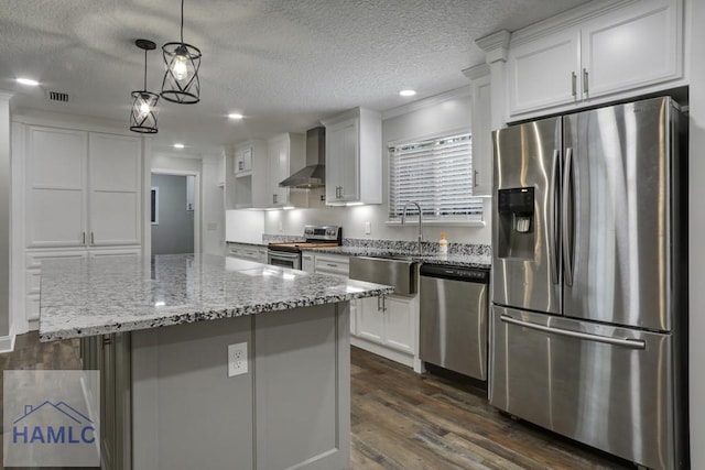 kitchen featuring dark wood-type flooring, a sink, stainless steel appliances, wall chimney exhaust hood, and white cabinets