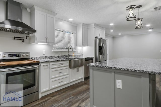 kitchen with dark wood-type flooring, light stone counters, appliances with stainless steel finishes, wall chimney exhaust hood, and white cabinets