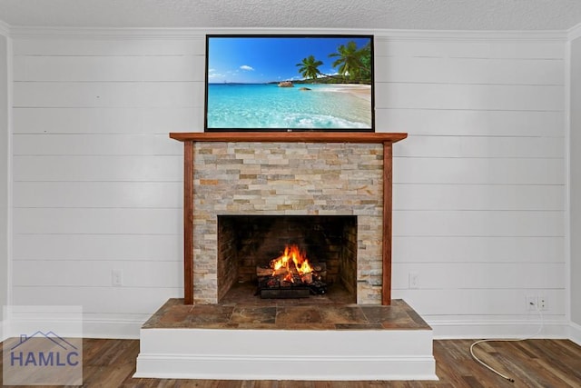 interior details with crown molding, baseboards, a lit fireplace, wood finished floors, and a textured ceiling