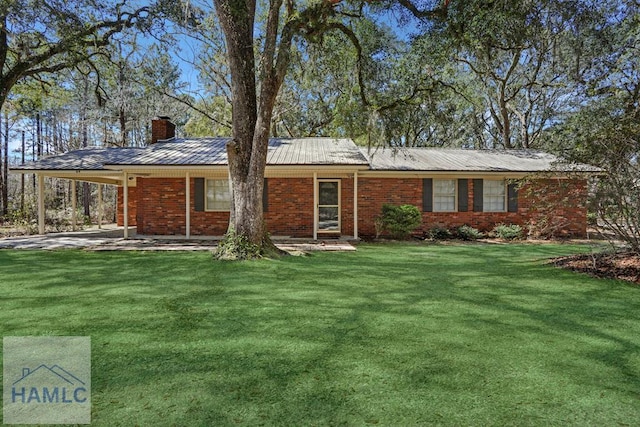 view of front of home with brick siding, a front yard, metal roof, an attached carport, and a chimney