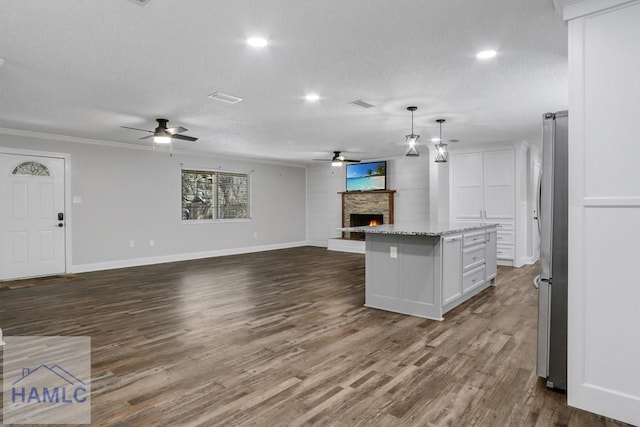 kitchen with open floor plan, a lit fireplace, freestanding refrigerator, dark wood-style floors, and a textured ceiling