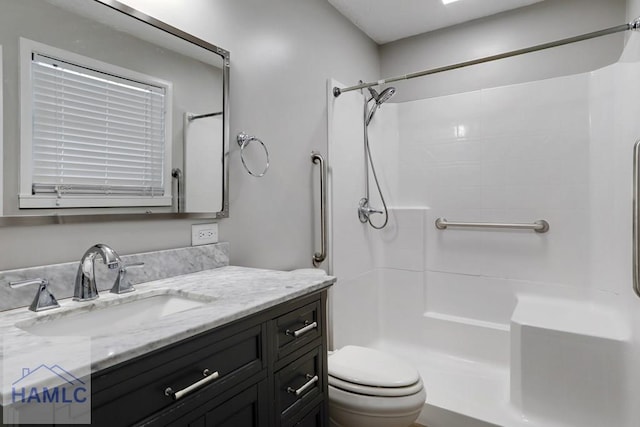 bathroom featuring toilet, vanity, and walk in shower