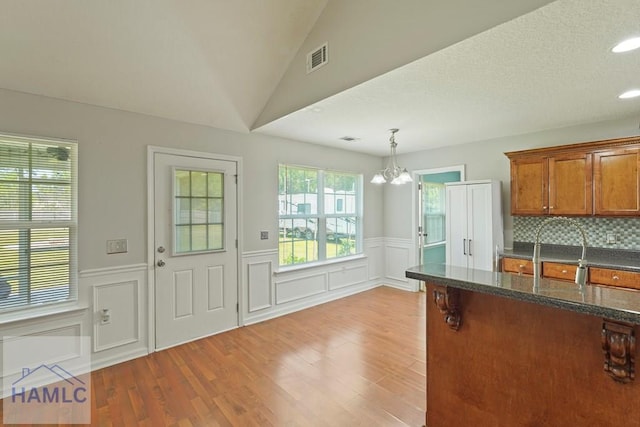 138 Forest St NE, Ludowici, GA 31316 - kitchen featuring light wood-style floors, a chandelier, brown cabinetry, wainscoting, and decorative light fixtures