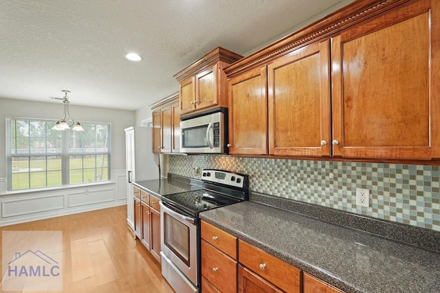138 Forest St NE, Ludowici, GA 31316 - kitchen featuring stainless steel appliances, dark countertops, brown cabinets, light wood finished floors, and backsplash