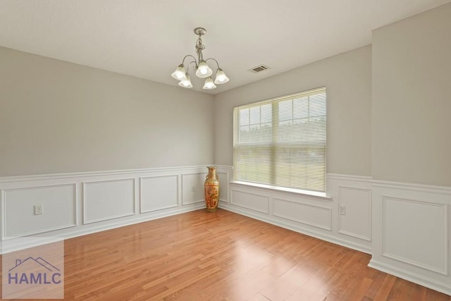 138 Forest St NE, Ludowici, GA 31316 - spare room featuring a chandelier, light wood-style floors, a wainscoted wall, and a decorative wall