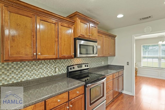 138 Forest St NE, Ludowici, GA 31316 - kitchen featuring stainless steel appliances, dark countertops, wood finished floors, brown cabinets, and decorative backsplash