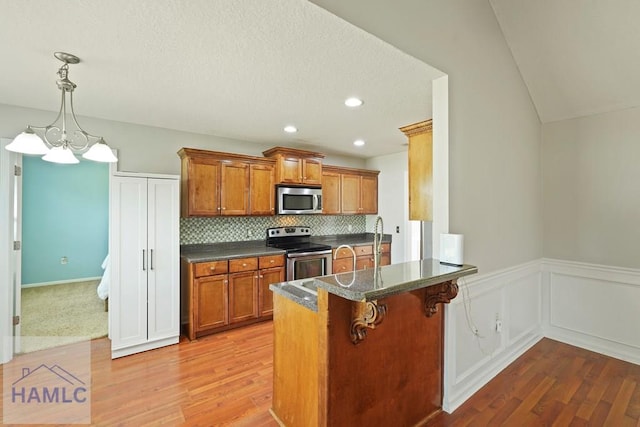 138 Forest St NE, Ludowici, GA 31316 - kitchen featuring stainless steel appliances, brown cabinets, dark countertops, light wood-style floors, and wainscoting