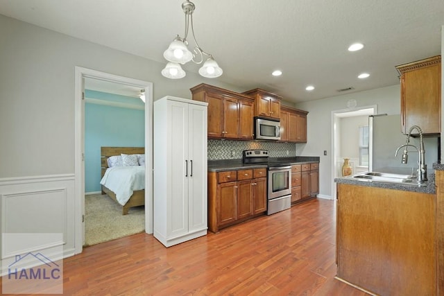 138 Forest St NE, Ludowici, GA 31316 - kitchen featuring appliances with stainless steel finishes, brown cabinetry, dark countertops, light wood-style floors, and tasteful backsplash